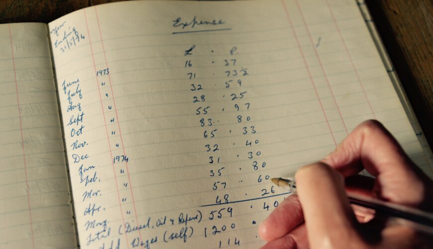 a hand holding a pen writing in an accounting book